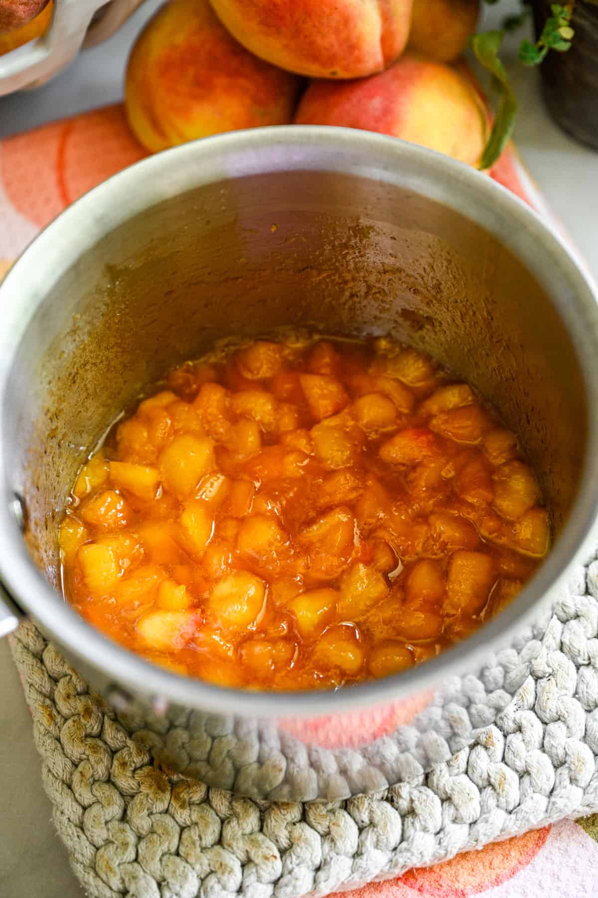 Bovenaanzicht van perzikcompote in een roestvrijstalen pan.