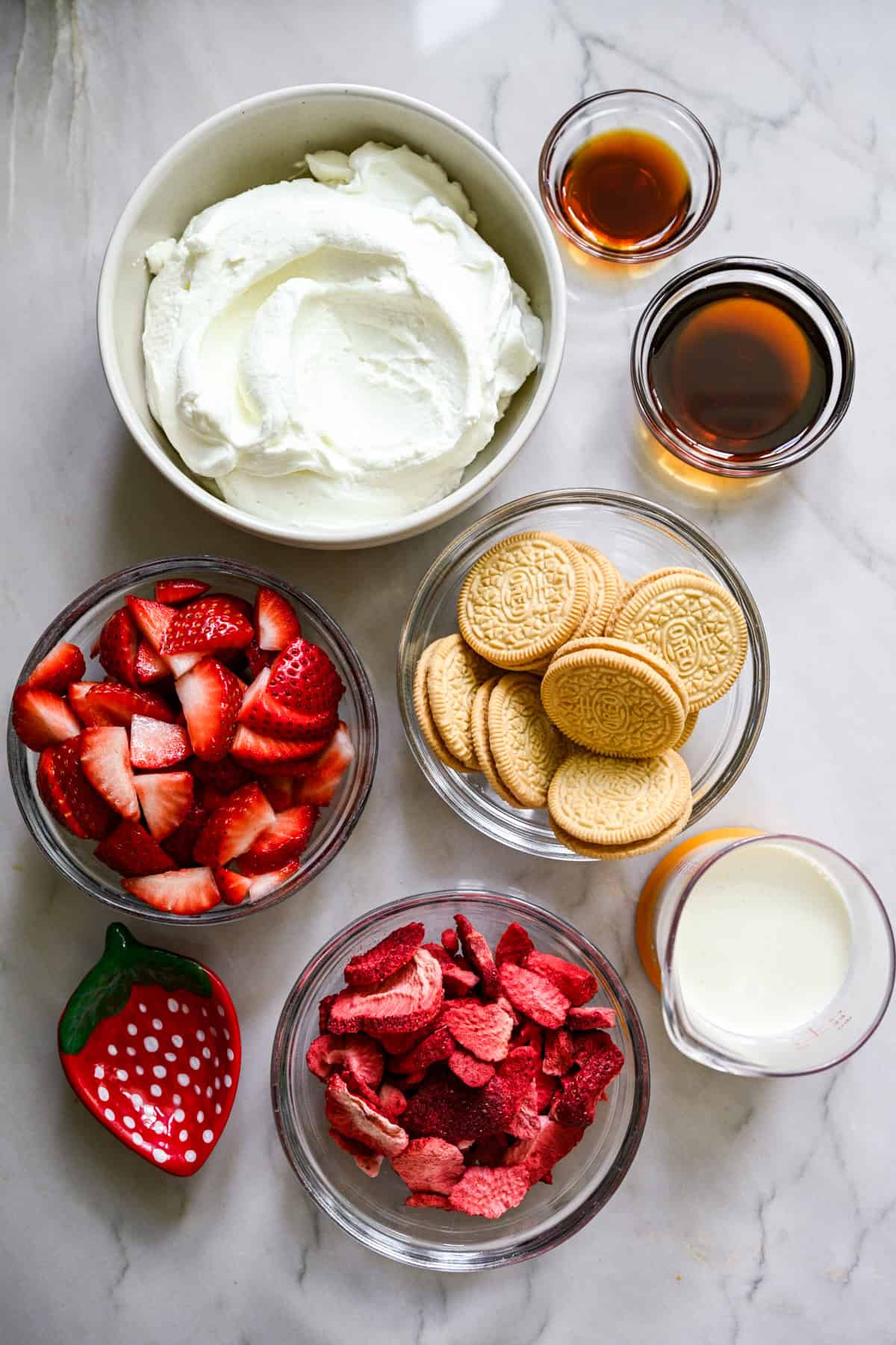 bovenaanzicht van ingrediënten voor aardbeien-shortcake-ijsrepen in kleine prep-kommen. 
