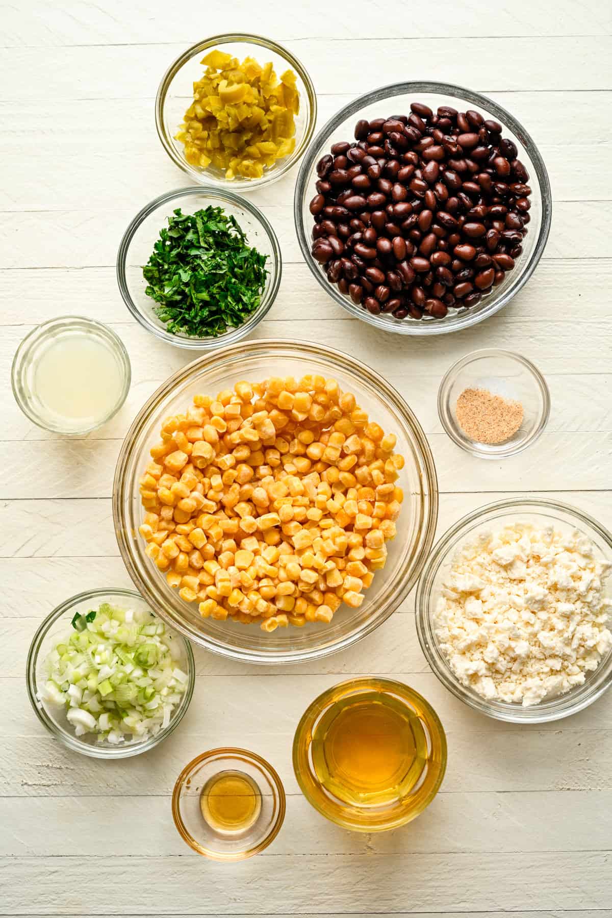 bovenaanzicht van ingrediënten voor zwarte bonen feta maïsdip in aparte kommen. 
