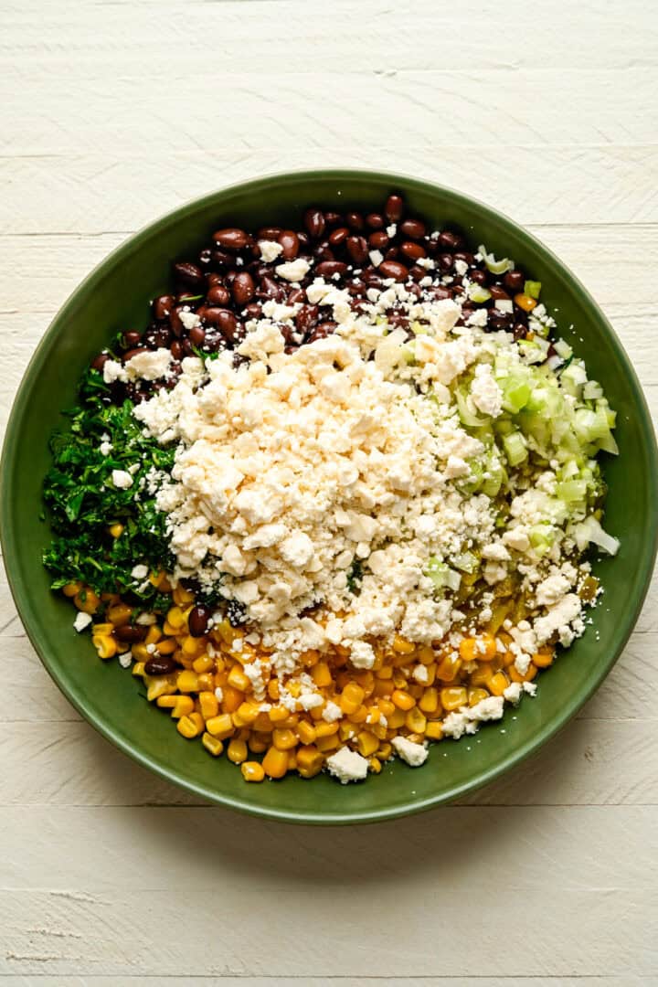 Ingrediënten voor de zwarte bonen-, maïs- en feta-dip in een kom voordat u ze mengt.