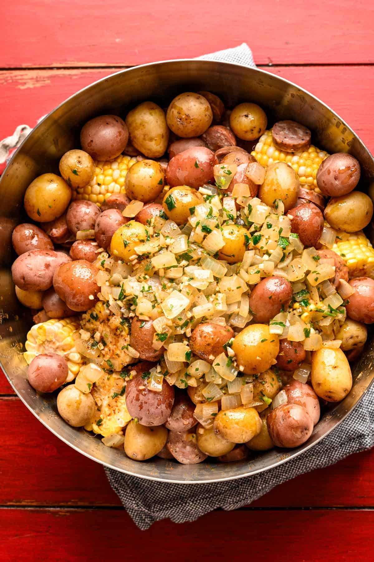 Garnalen, maïs, aardappelen en worst in een grote kom met oude laurier-knoflookbotersaus erover gegoten voordat ze worden gemengd.