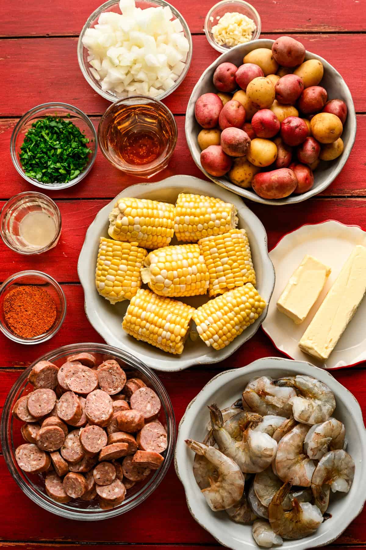 Bovenaanzicht van ingrediënten voor bladpangarnalen koken op een rode tafel in aparte kommen. 