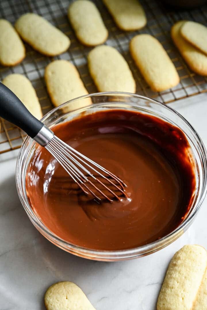 chocoladeganache in een mengkom met een garde.
