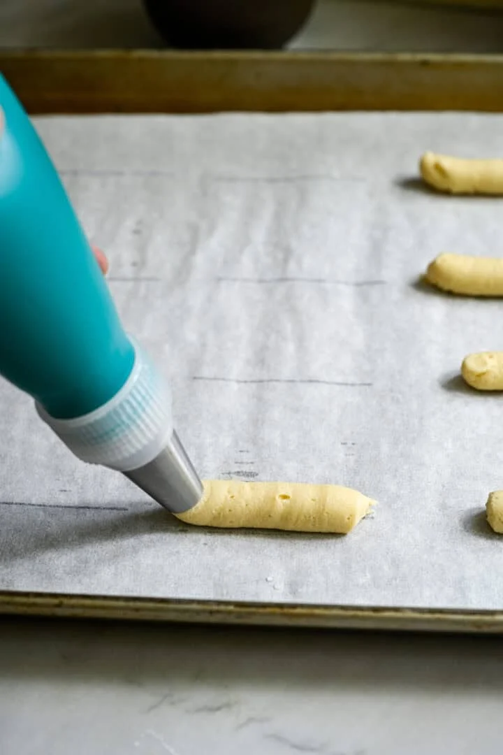 koekjesdeeg in een rechte lijn op een bakplaat spuiten.