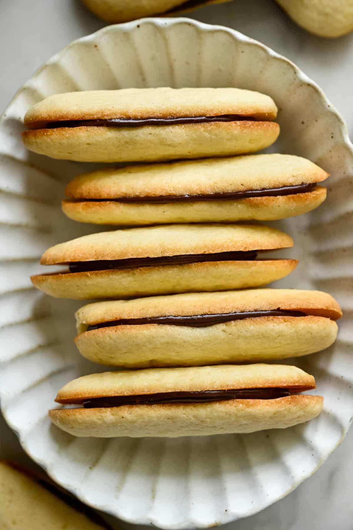 bovenaanzicht van een stapel zelfgemaakte milanokoekjes in een witte ovale kom.