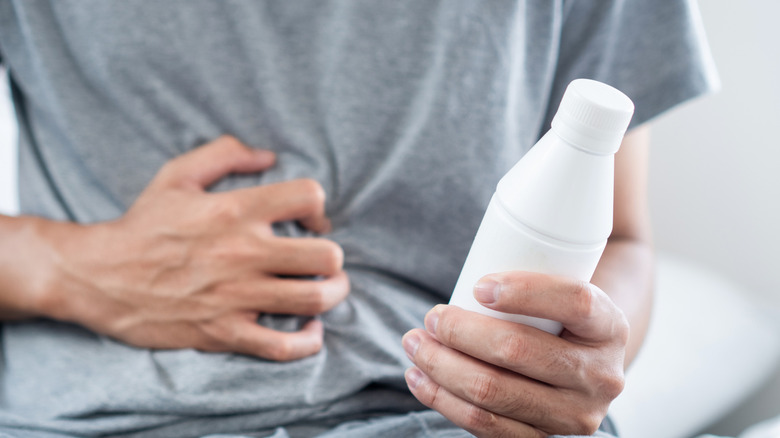 Een man die een fles maagzuurremmer in zijn hand houdt om symptomen van zure reflux, brandend maagzuur of indigestie te verlichten