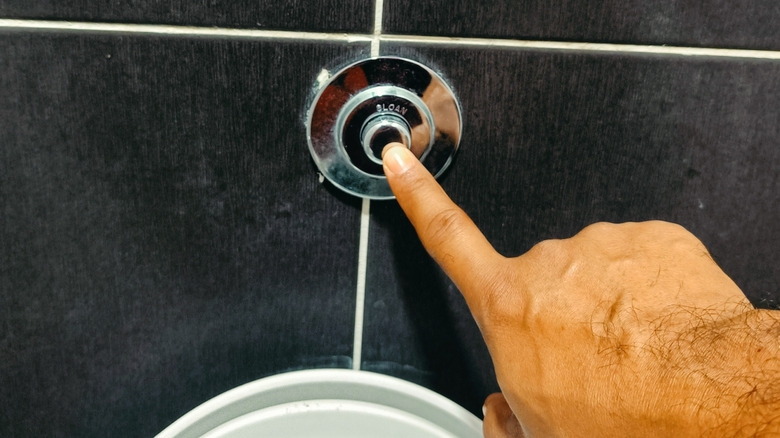 persoon die op de spoelknop voor het toilet drukt