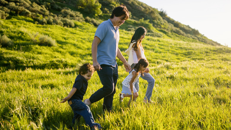 vader, moeder en twee kinderen lopen in het grasveld