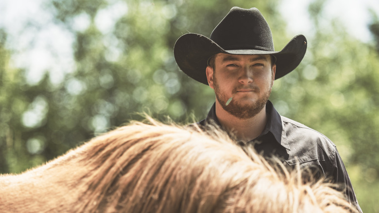 Een cowboy die achter zijn paard staat