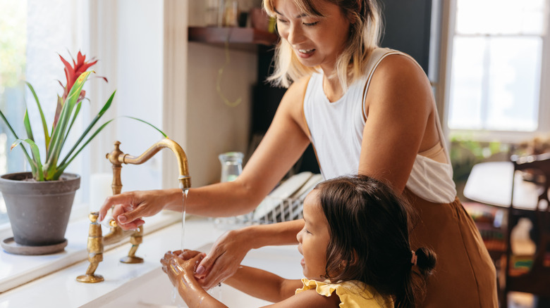 vrouw en kind handen wassen bij de gootsteen
