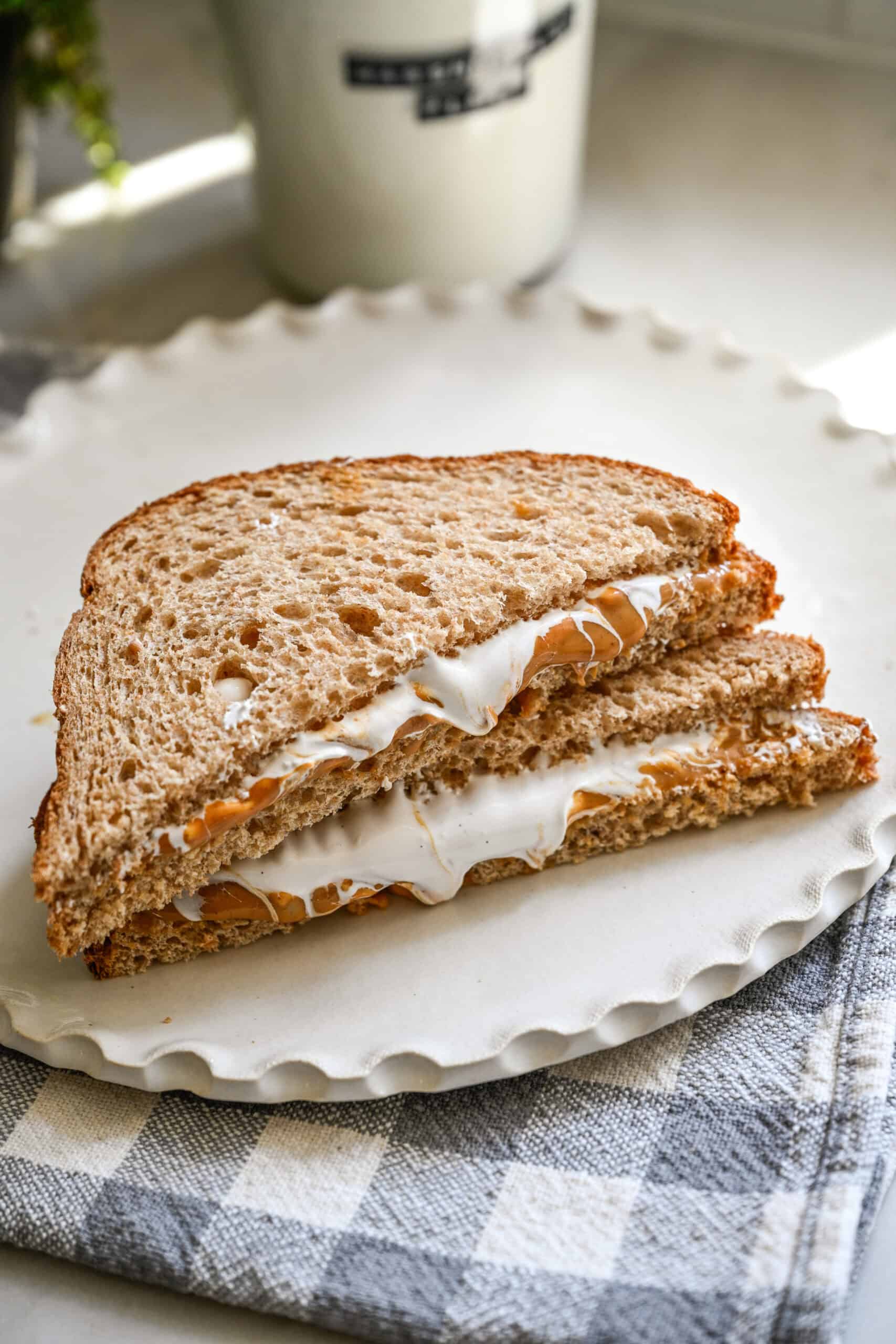 Fluffernutter-sandwich met pindakaas en marshmallow-pluisjes, in tweeën gesneden op een bord.