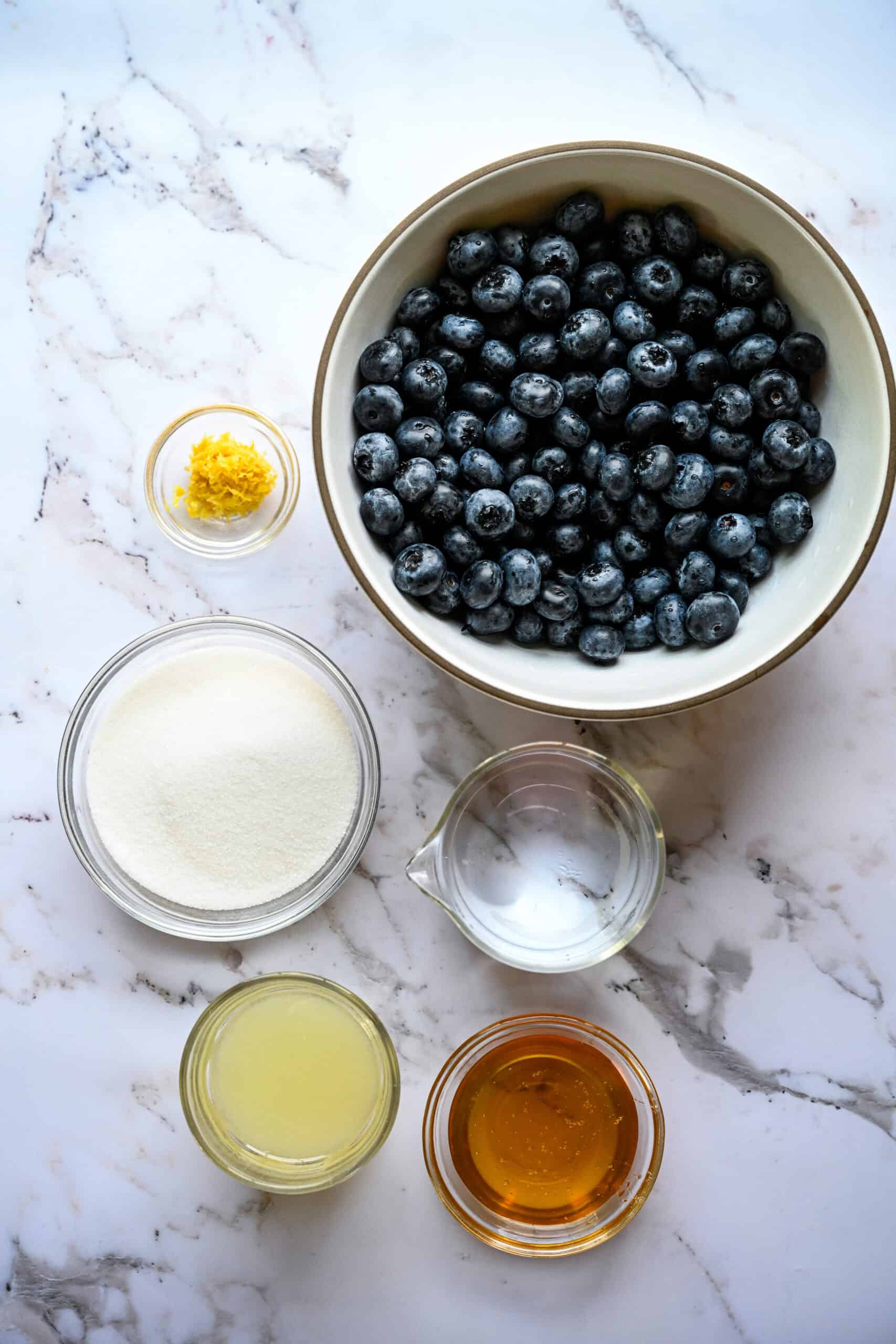 bovenaanzicht van ingrediënten voor bosbessengranita in kleine kommen.