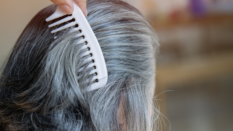 vrouw loopt kam door grijs haar