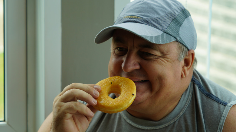 Senior man die lacht terwijl hij een donut eet