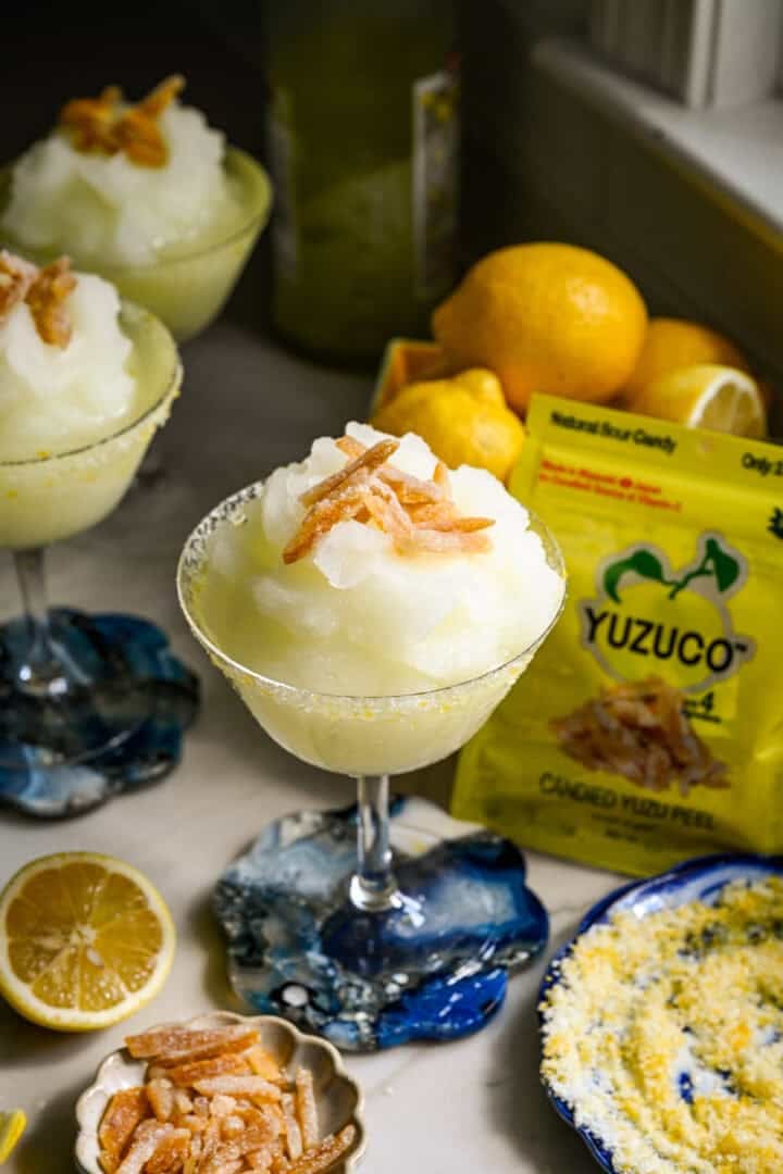 close-up van bevroren limoncello-cocktail in een coupéglas met gekonfijte yuzu-schil garnituur.