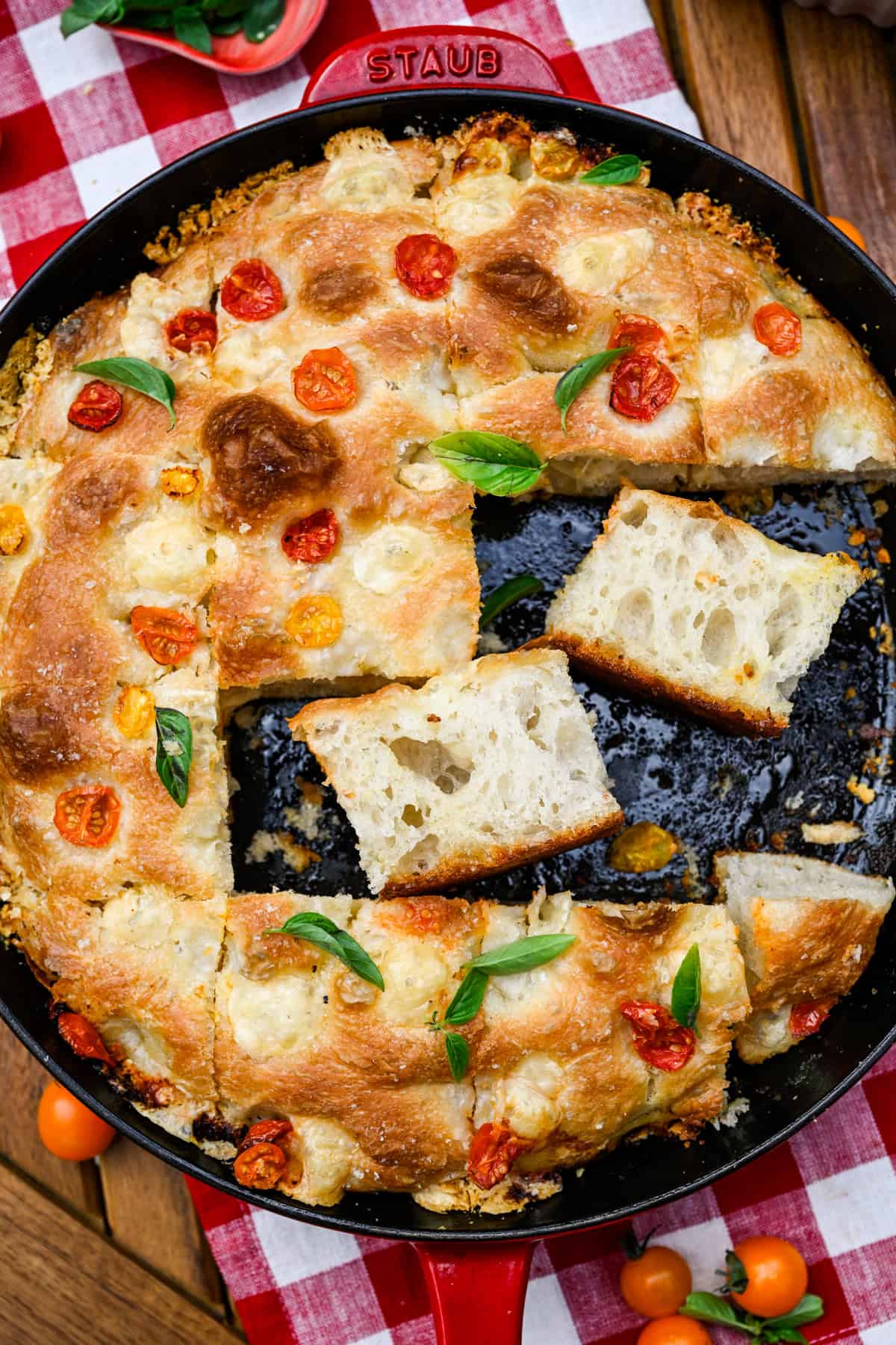 Focaccia van tomatenbasilicum in een koekenpan met twee plakjes op hun zijkant.