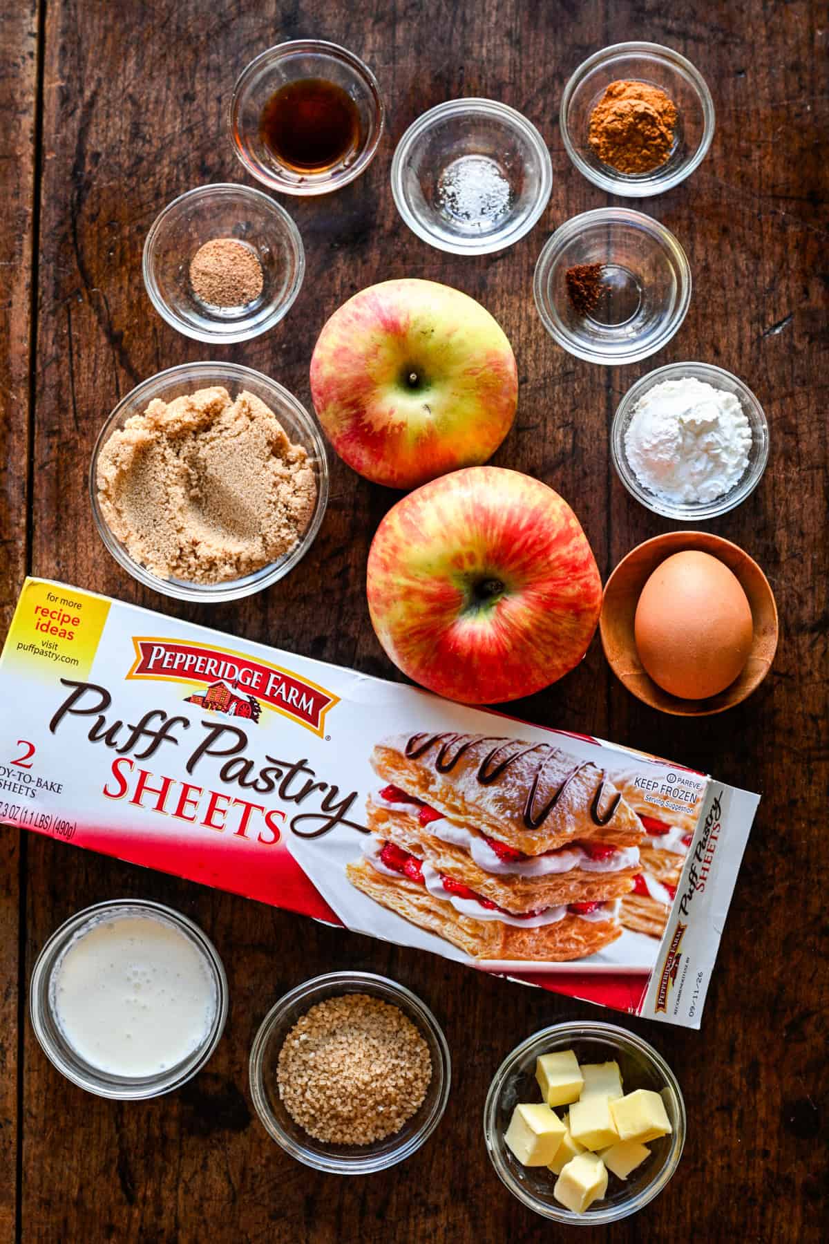 Bovenaanzicht van mini-appeltaartingrediënten, waaronder appels en bladerdeeg.