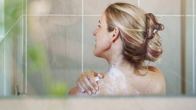 vrouw onder de douche die een stuk zeep gebruikt om schoon te worden