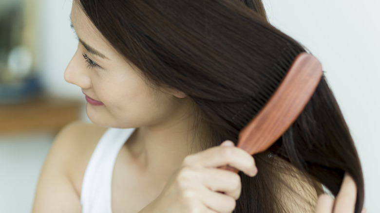 vrouw die lacht en haar haar borstelt