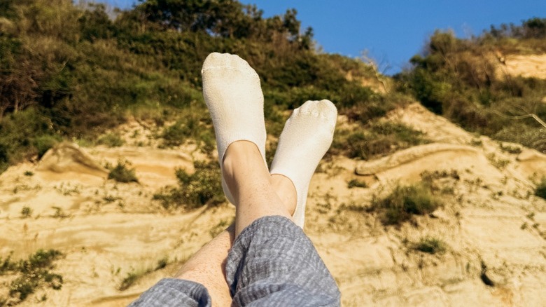 Een persoon die witte sokken draagt ​​terwijl hij op een zandstrand rust