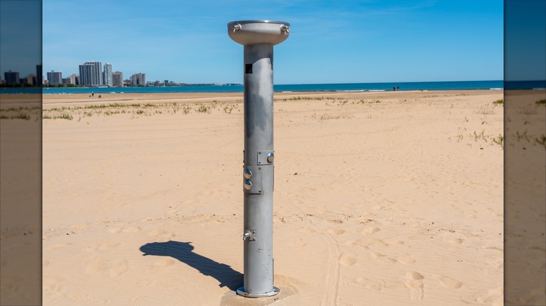 Een metalen openbare buitendouche op een zandstrand