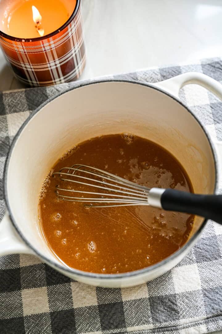 Boter en ahornsiroop samengeklopt in een kleine witte pan.