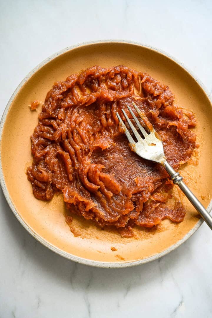 Gepureerde dadels op een gele plaat met een vork.