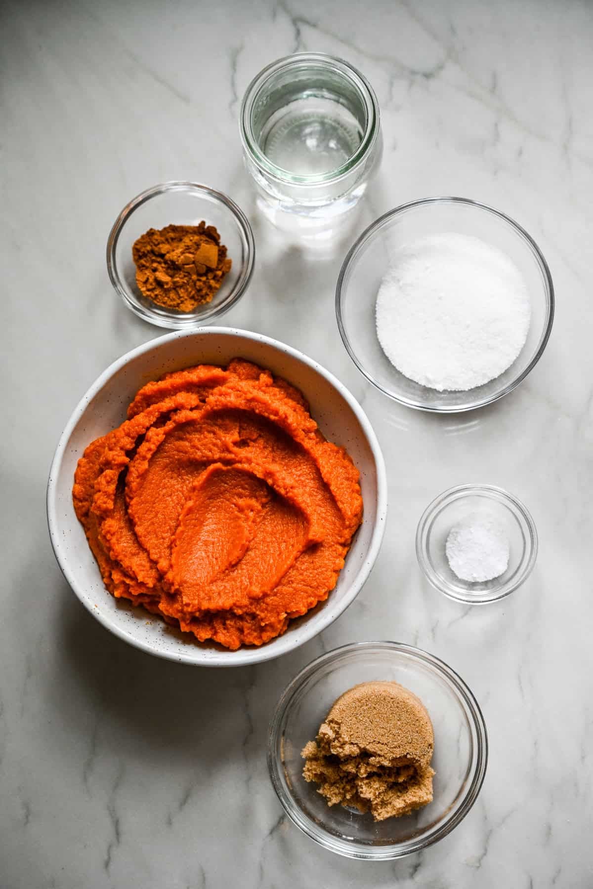 bovenaanzicht van ingrediënten voor zelfgemaakte pompoenboter in kleine prep-kommen.