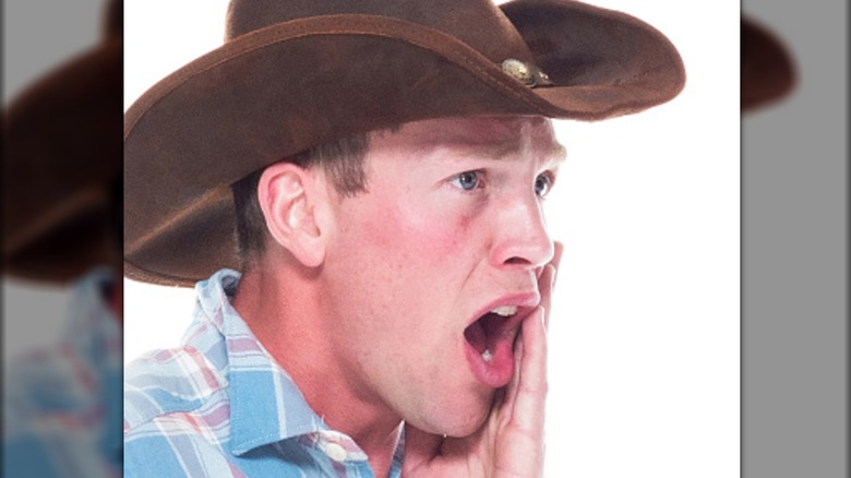 Cowboy houdt zijn wang ongemakkelijk vast en schreeuwt