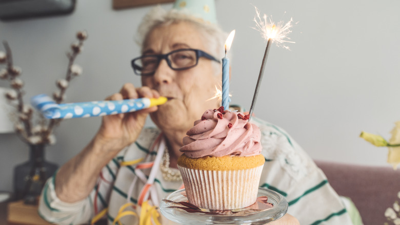 oudere vrouw die thuis een speciale gelegenheid viert met een cupcake