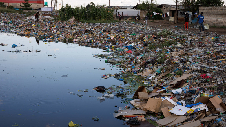 Er ligt afval in een hoeveelheid vervuild water nabij een woongemeenschap in Lusaka, Zambia