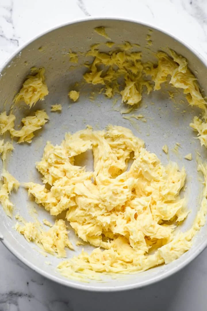 Bleek, donzig afgeroomd botermengsel in een grote gespikkelde mengkom.
