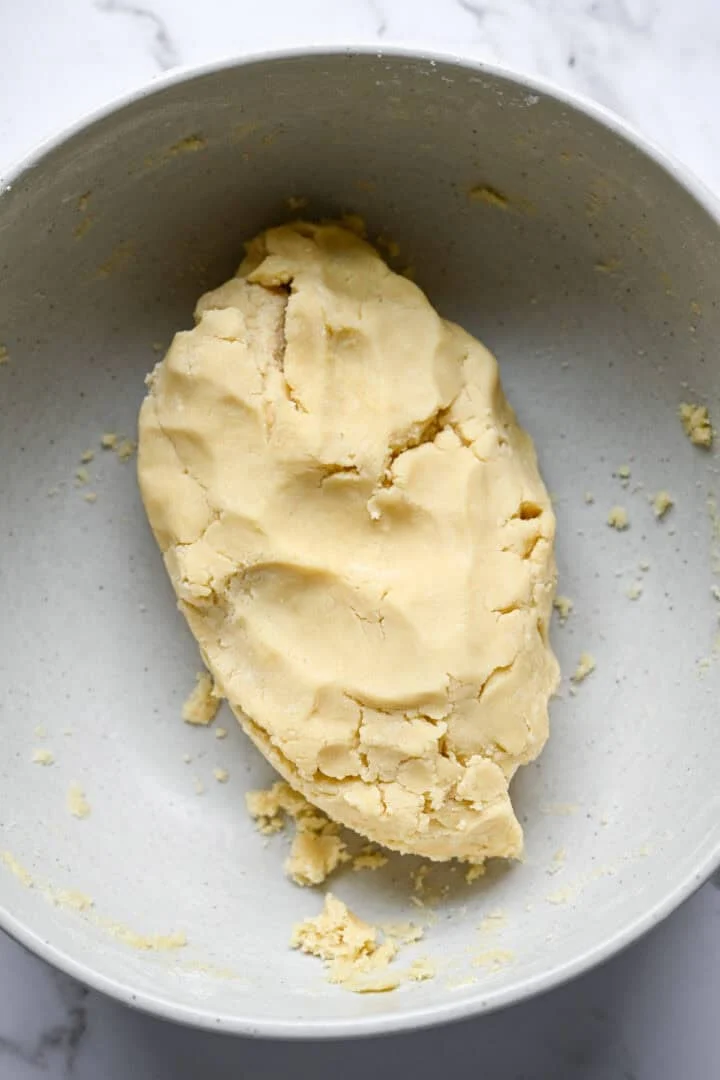 Gladde berg zandkoekdeeg in een grote gespikkelde mengkom met een paar kruimels eromheen.