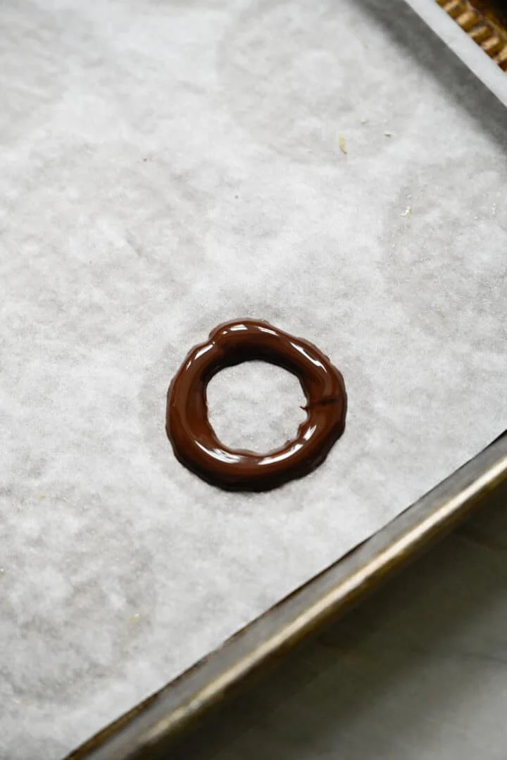 Ring van gesmolten pure chocolade op een met bakpapier beklede bakplaat.