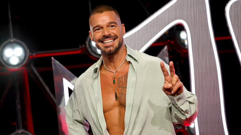 Ricky Martin maakt een vredeshandgebaar terwijl hij op het podium staat van een openbaar evenement