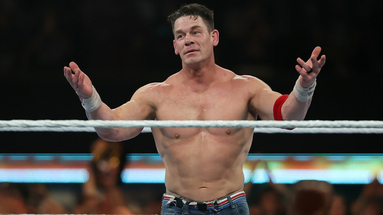 John Cena steekt tijdens een wedstrijd beide handen op naar het publiek in een worstelring