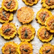 Close-up bovenaanzicht van gevulde delicata-pompoenringen rond een enkele Parmezaanse kaaschips.