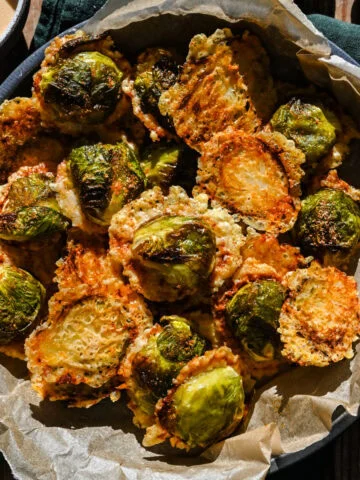 Krokant geroosterde spruitjes met Parmezaanse kaas in een zwarte kom.