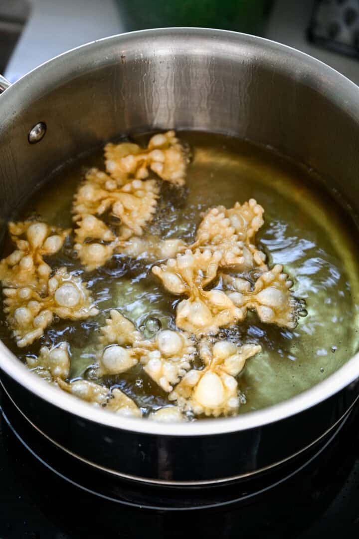 Close-up van strikje pasta puffend in hete olie in een pan.