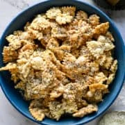 Bovenaanzicht van een blauwe kom gepofte pasta bestrooid met Parmezaanse kaas en gebarsten peper.