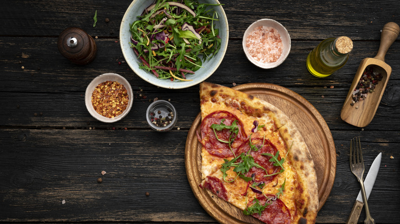 Pizza naast salade en andere ingrediënten