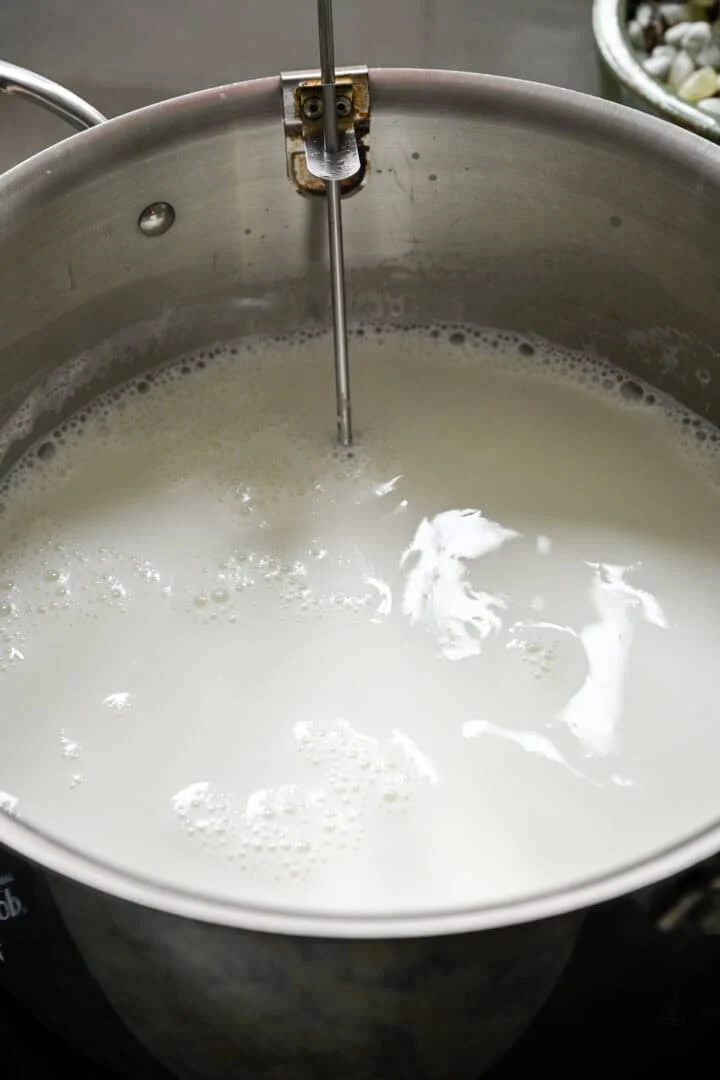 Verwarmen van volle melk in een grote roestvrijstalen pan met clip-on thermometer