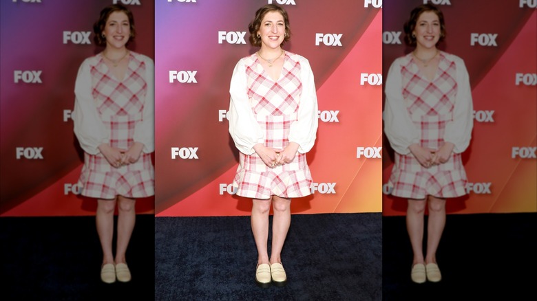 Mayim Bialik poseert tijdens een beroemdheidsevenement in een roze en witte jurk