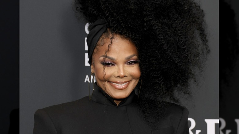 Janet Jackson glimlacht tijdens een beroemdheidsevenement in een zwarte outfit